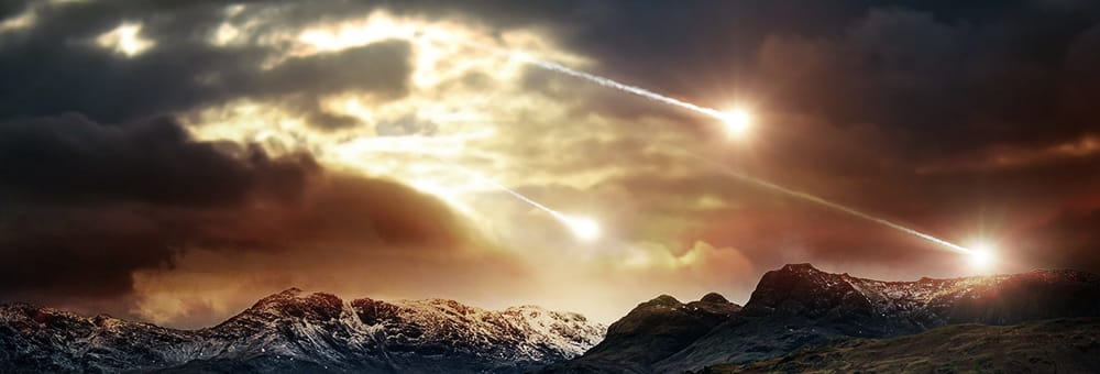 A cloudy sky over a mountain range, illuminated by three falling meteors.